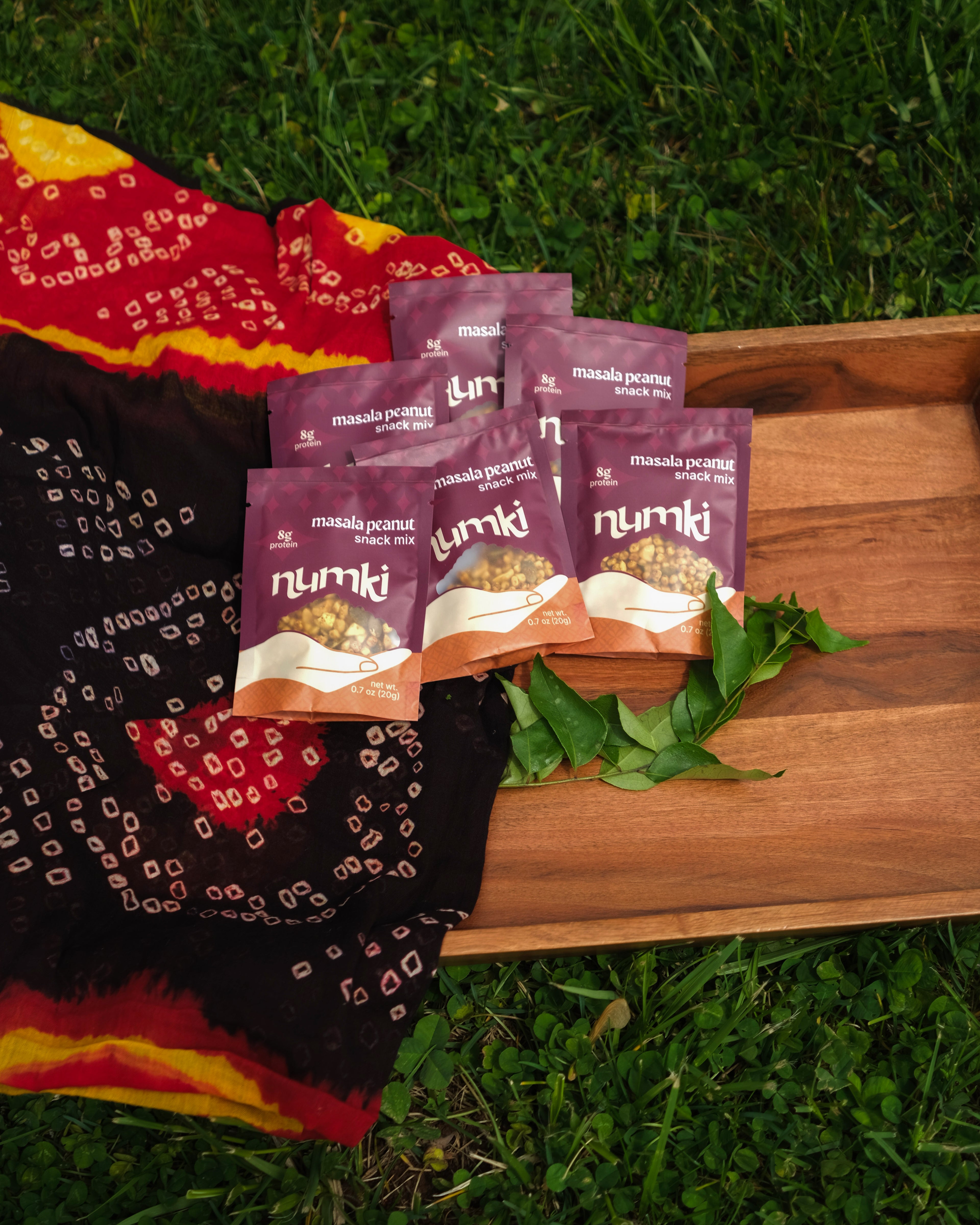 Six Numki Masala Peanut pouches on a wooden tray